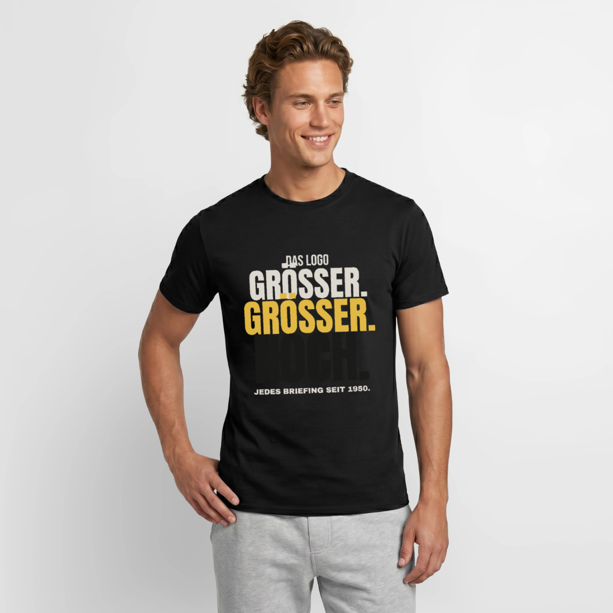 "Das Logo größer. Größer. Noch. Jedes Briefing seit 1950." Motiv-T-Shirt für Männer, Farbe Schwarz, Model